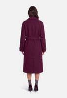 Frau trägt burgunderroten Trenchcoat mit Gürtel, schwarze Pumps und graue Socken.