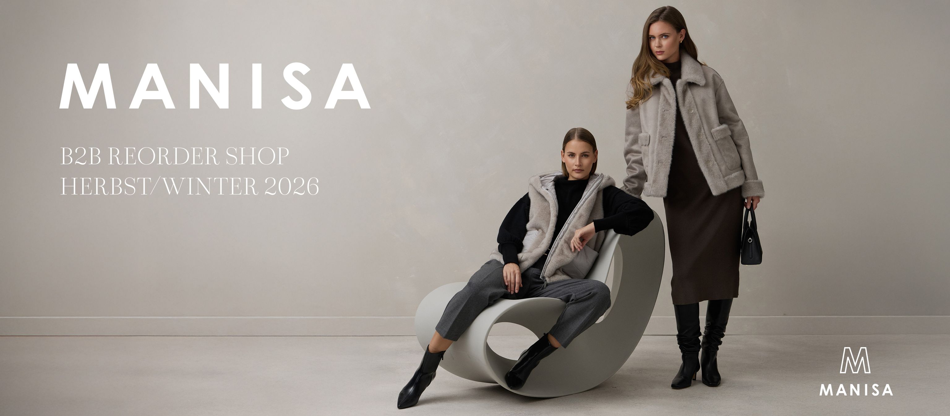 Modisches Herbst-Winter 2026 Outfit: Zwei Frauen in stylischen Jacken und Accessoires vor grauer Couch.