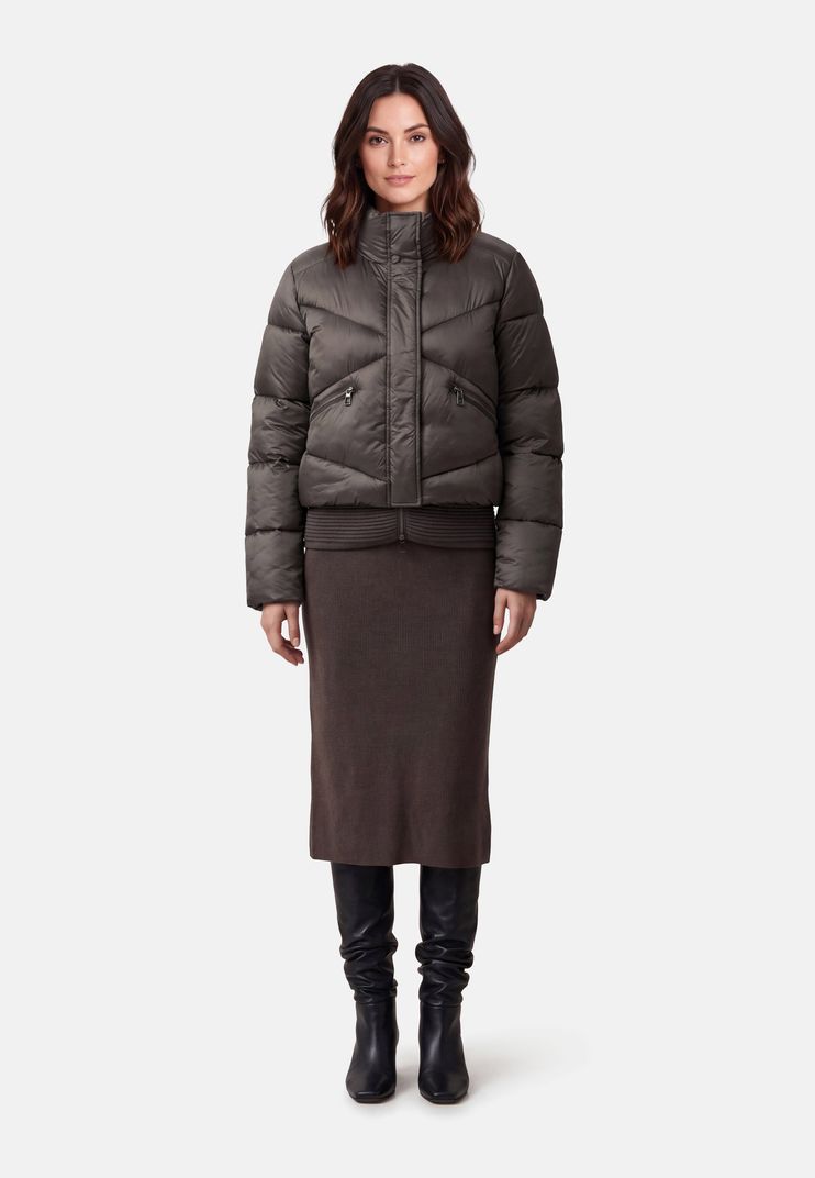 Frau trägt olivgrünen Daunen-Jackenkleid mit weitem Rock und schwarzen Stiefeln.