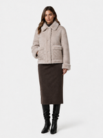 Frau trägt beige Schaffelljacke mit Pailletten, braunen Rock und schwarze Stiefel.